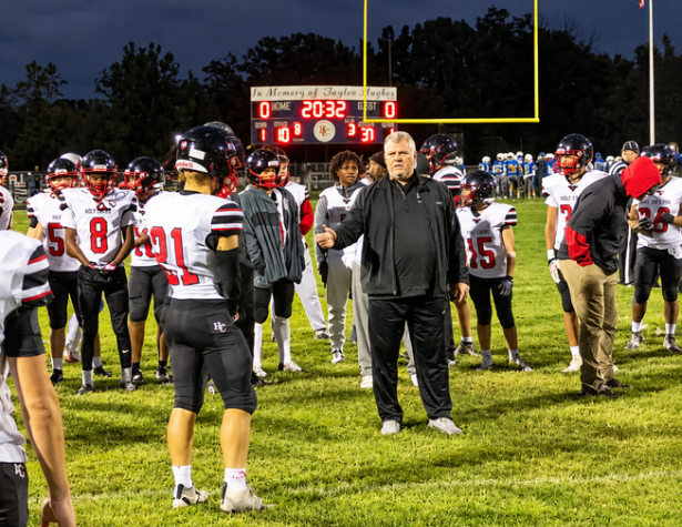 Holy Cross football players gather around their coach on the field at Trimble County during Week 9 of the 2026 high school football season.